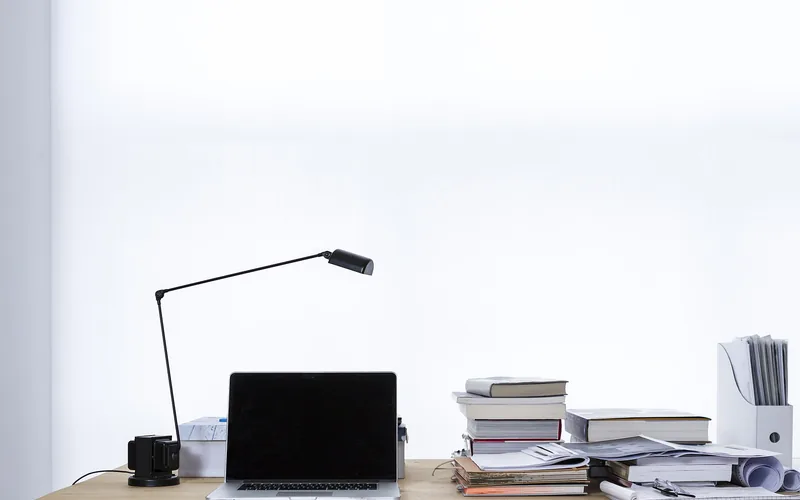 Laptop, Leselampe und Bücherstapel